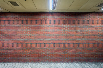 Dark brick wall in indoor walkway. The bricklayer pattern made by mixed stretchers and soldiers.