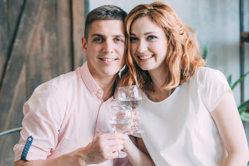 Portrait of young happy couple with glasses at table
