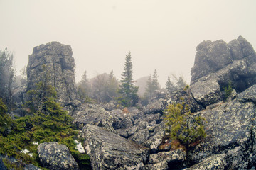 Dark mountain landscape with big mysterious rocks covered by fog