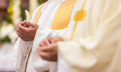 Priest' hands during a wedding ceremony/nuptial mass (shallow DOF; color toned image)