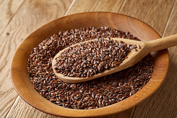 Wooden spoon with flax seeds in a plate on rustic background, top view, close-up, shallow depth of field