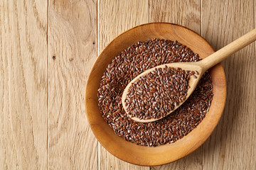 Wooden spoon with flax seeds in a plate on rustic background, top view, close-up, shallow depth of field
