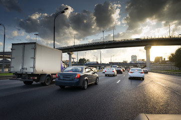 Cars on highway road at sunset. Overpass and busy road
