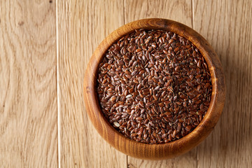 Flax seeds in wooden bowl on rustic wooden background, top view, shallow depth of field