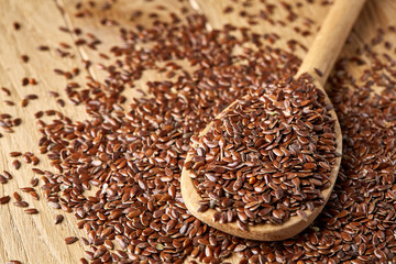Flax seeds in wooden bowl and spoon on rustic wooden background, top view, shallow depth of field
