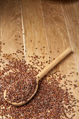Flax seeds in wooden bowl and spoon on rustic wooden background, top view, shallow depth of field