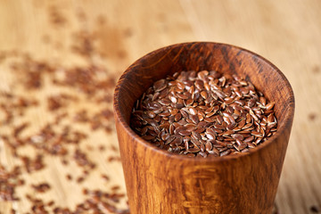 An overturned wooden bowl with linseeds on a rustic background, close-up, shallow depth of field, selective focus