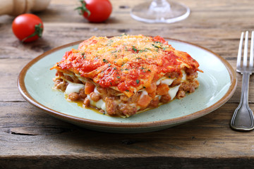 lasagna tradizionale italiana con salsa bolognese e parmigiano su sfondo rustico