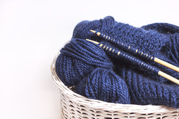Knitting yarn balls and needles in white wooden basket on  white background. Hobby creative backdrop with copy space