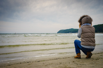 Woman walking on beach, autumn cold day