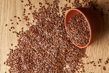 An overturned ceramic bowl with linseeds on a rustic background, close-up, shallow depth of field, selective focus