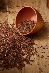 An overturned ceramic bowl with linseeds on a rustic background, close-up, shallow depth of field, selective focus