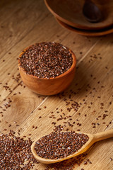 Wooden spoon with flax seeds on rustic background, top view, close-up, shallow depth of field, selective focus
