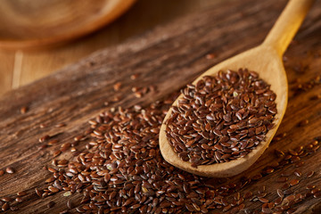 Wooden spoon with flax seeds on rustic background, top view, close-up, shallow depth of field, selective focus
