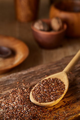 Wooden spoon with flax seeds on rustic background, top view, close-up, shallow depth of field, selective focus