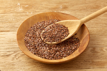 Wooden spoon with flax seeds on rustic background, top view, close-up, shallow depth of field, selective focus