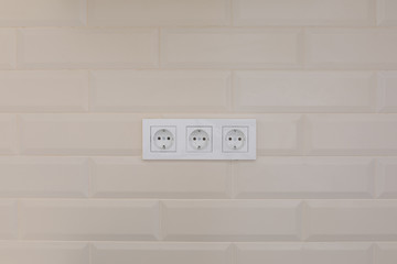 electric socket on a white tiled wall