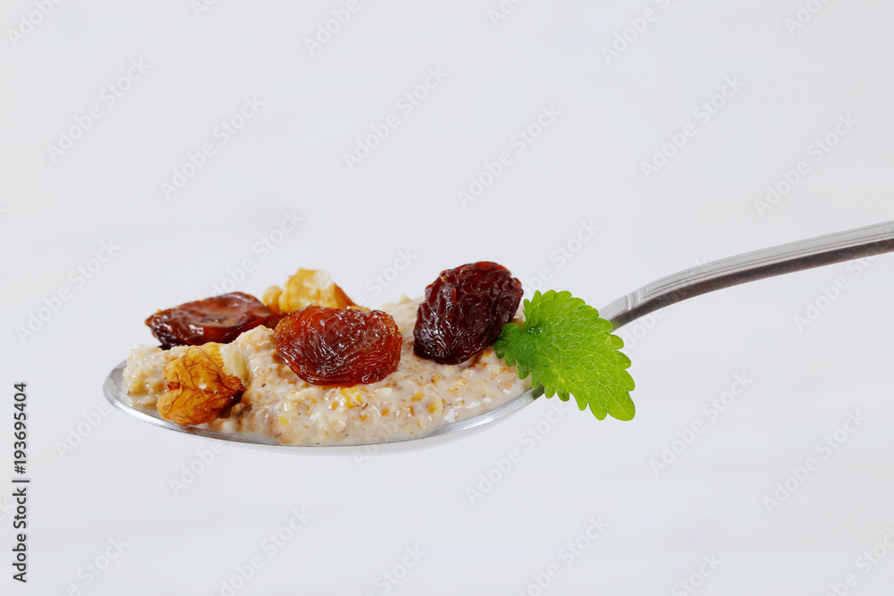 Poster spoon of oatmeal porridge with raisins and walnuts