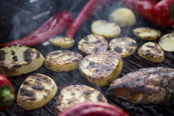 Fototapeta na wymiar Hot Outdoor BBQ Grill With A Cut Potatoes Pieces, Red Peppers And Tasty Chicken Breast Meat