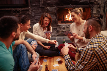 Smiling friends partying together and playing cards