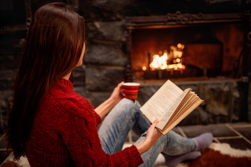 Fototapeta na wymiar girl reading book in front of fireplace and relaxing