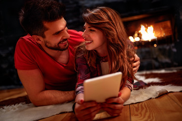 Romantic couple laying on floor and using tablet at home
