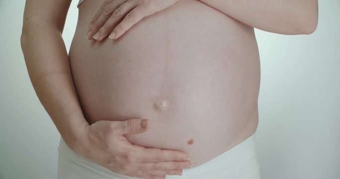 pregnant girl stroking her belly hands while wiggling baby