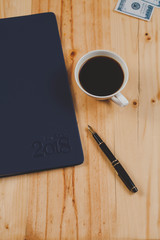 personal organizer or planner with fountain pen and hot coffee on wood table.