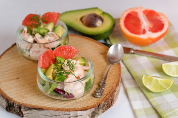 Cocktail salad with shrimp, avocado, green lettuce, grapefruit and mayonnaise sauce in a glass.