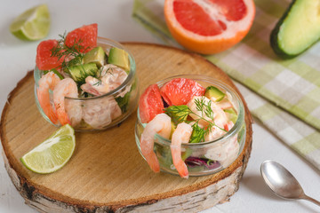 Cocktail salad with shrimp, avocado, green lettuce, grapefruit and mayonnaise sauce in a glass.