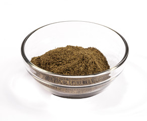 Ground black pepper in a glass dish on a white background.