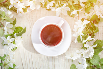 Mug of tea and apple blossom on a wooden background. Top view