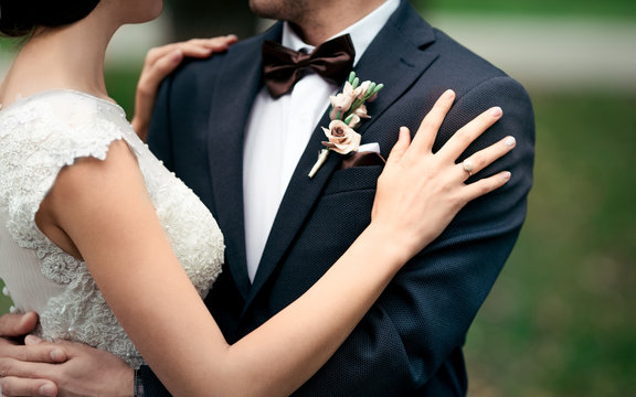 Wedding moment, couple of newlyweds, stylish bride and groom hug while on a walk in the park. The newlyweds hold hands