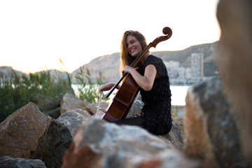 Happy young beautiful girl with her cello on the outside