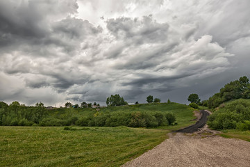 view from a rural road on the background of storm clouds