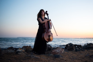 Young beautiful girl with her cello on the outside © luismolinero