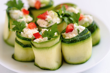 Rolls of zucchini stuffed with cheese and chives and red paprika.