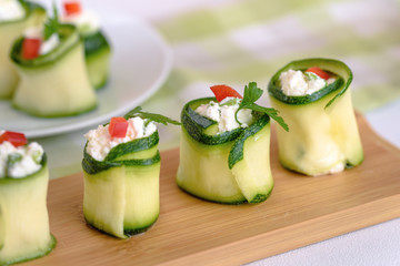 Rolls of zucchini stuffed with cheese and chives and red paprika.