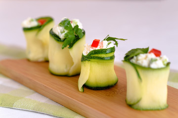 Rolls of zucchini stuffed with cheese and chives and red paprika.