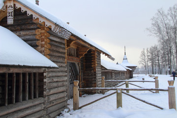 Traditional a hail from logs of the Russian Christian wooden church covered with snow in cloudy winter day in a hard frost.