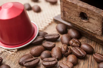 Fotobehang dosette de café expresso avec grains de café et ancien moulin à café décoratif sur sur table en bois © pixarno
