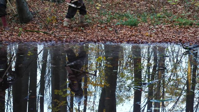 Medieval Vikings walking through the forest reflected in water.