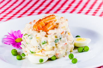 Salad Olivier with crayfish and chicken on white plate