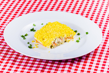 Salad Mimosa with vegetables on white plate. Russian cuisine