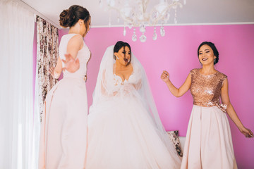 Bride and bridesmaids having fun and jumping on the bed at wedding morning