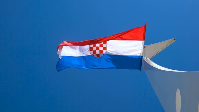 Croatia flag waving in the wind against blue sky in summer in harbor of Split old town in Croatia.