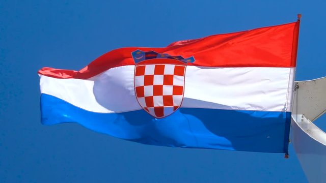 Croatia flag waving in the wind against blue sky in summer in harbor of Split old town in Croatia.