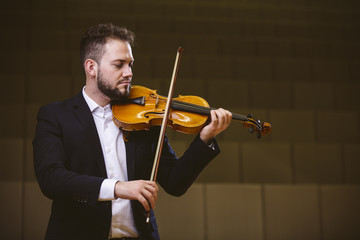 Violinist. Image of a man violinist in a concert hall. The young violinist wears a suit.