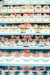luxury wedding catering, table with modern desserts, cupcakes, sweets with fruits. delicious candy bar at rich wedding reception. space for text. shower. holiday celebration
