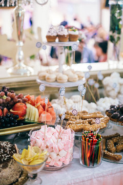 luxury wedding catering, table with modern desserts, cupcakes, sweets with fruits. delicious candy bar at rich wedding reception. space for text. shower. holiday celebration
